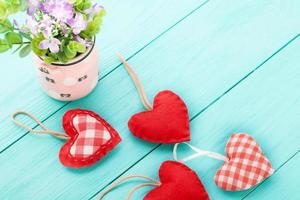 Vase of flowers and hearts on blue wooden background with copy space. photo