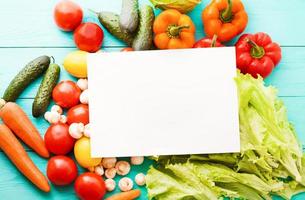 Recipe paper with vegetables on blue table. Top view photo