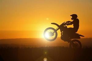 Silhouette of a motocross motorcycle lifting the front wheel. Adventure and Action Concepts photo