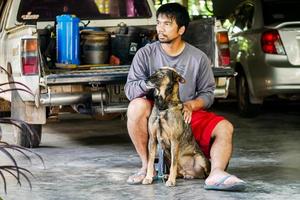 Asian man sits with a dog in his home photo