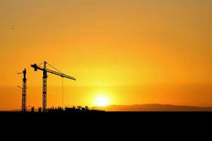 Silhouette of a crane in a construction site. Crane concept for the construction industry photo