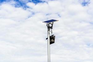 pequeño panel solar para luz en la calle o parque con nubes blancas y cielo azul. poste de iluminación exterior con energía de panel solar de tamaño pequeño por sí mismos, nueva tecnología y tendencia energética para áreas públicas foto