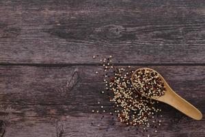 Quinoa seeds in the wooden spoon on wooden background.  Quinoa is a good source of protein for people following a plant-based diet. photo
