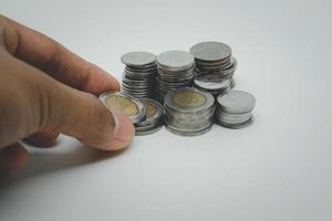 Close up hand picking or adding baht coin  isolated with white background. Saving money concept. photo