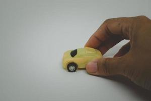 Hand with yellow toy car isolated on white background. photo