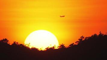 Passenger airliner flying by on the background of setting sun,
