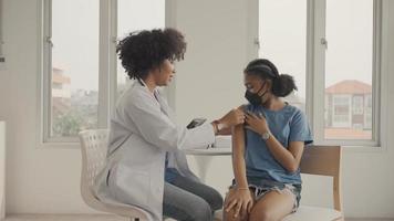 un médecin afro-américain applique du plâtre sur l'épaule d'un enfant après avoir été vacciné. ouverture des manches pour vacciner contre la grippe ou l'épidémie dans les soins de santé et le concept vacciné. video