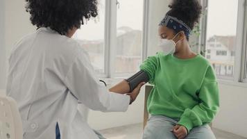 médico americano africano está medindo a pressão arterial e verificando o pulso do paciente infantil. video