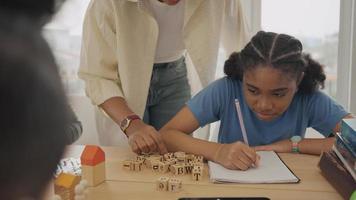 African American female teacher standing with pupils teaching writing lesson in modern classroom. video