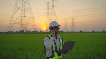 ingeniero eléctrico con una laptop hablando por teléfono torre de alta tensión video