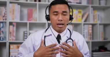 Close up of Professional asian male doctor in white medical coat. Man headset making conference call and looking at camera. Consulting distance patient online by webcam. Telemedicine concept. video