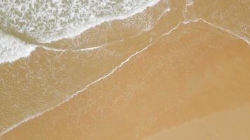 vista aérea de la playa de arena y la textura de la superficie del agua. olas espumosas con cielo. hermosa playa tropical. increíble costa de arena con olas de mar blanco. concepto de naturaleza, paisaje marino y verano. video