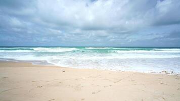 praia de areia do oceano azul e textura da superfície da água. ondas espumosas com céu e nuvens. bela praia tropical. incrível litoral arenoso com ondas do mar branco. conceito de natureza, marinha e verão. video