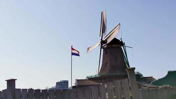 oude nederlandse windmolens door de zaanse schans en nederlandse vlag, reisreportage video