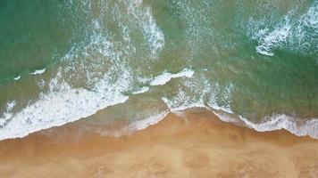 vue aérienne de la plage de sable blanc et de la texture de la surface de l'eau. vagues mousseuses avec ciel. belle plage tropicale. incroyable littoral sablonneux avec des vagues de mer blanche. nature, paysage marin et concept d'été. agrandir. video