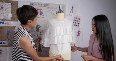 Nahaufnahme einer asiatischen Lehrerin, die Modestudentin mit Maßband auf Puppe im Studio unterrichtet. modedesigner, ausbildungs- und bildungskonzept.
