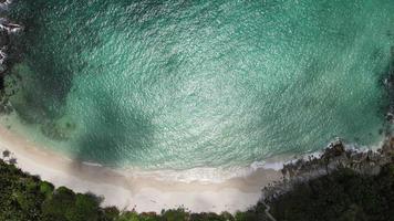Aerial view zoom in of sand beach and water surface texture. Foamy waves with sky. Beautiful tropical beach. Amazing sandy coastline with white sea waves. Nature, seascape and summer concept. video