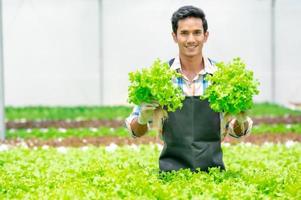 hombre asiático feliz en la granja de verduras hidropónicas foto