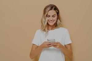 Young happy girl using smartphone, chatting with boyfriend in social media and smiling photo