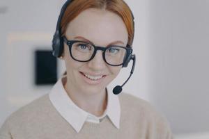 Online consultant of call center. Young woman in earphones provides information by telephone. photo