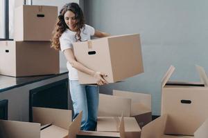 Happy curly girl carrying box and relocating. Real estate and property advertising mockup concept. photo