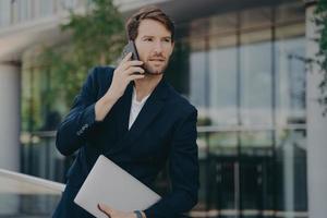 Intelligent businessman speaks on phone during walk to office photo