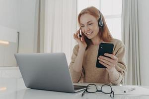 una empleada con auriculares tiene una conferencia de videollamada y un teléfono inteligente moderno foto