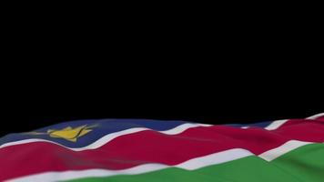 Namibia tygflagga vajar på vindslingan. namib broderi stickad tyg banner vajande på vinden. halvfylld svart bakgrund. plats för text. 20 sekunders loop. 4k video