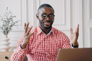 Overjoyed afro american businessman in glasses reading great news on laptop at workplace photo
