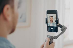 apuesto joven vlogueando o grabando video en un teléfono inteligente foto