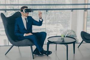 Overjoyed office worker wears VR headset, enjoying spending coffee break time in virtual reality photo