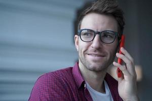 Millennial european man talking on smartphone while working distantly online from home photo