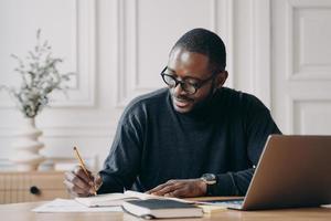 Confident young Afro american businessman working remotely online while sitting at home office photo