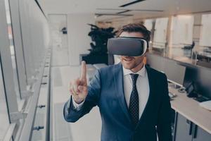 Young businessman in elegant suit using VR headset, touching exploring virtual reality at work