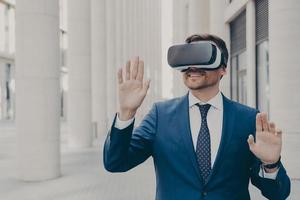 Professional male architect in augmented reality headset gesturing while standing outdoors photo