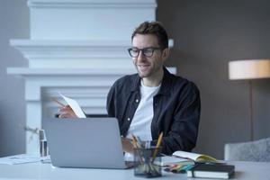 Young sitisfied male entrepreneur in glasses talking speaking during web conference via internet photo