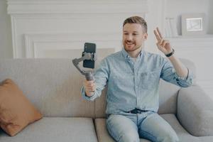 Young man showing peace gesture while video chatting photo