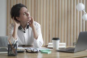 Overworking remote call center operator lady suffers from fatigue and neck pain photo