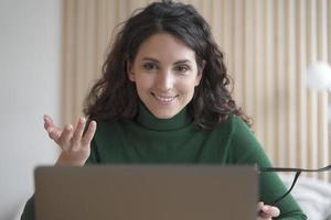 una joven italiana sonriente profesora tutora habla con los estudiantes durante la lección en línea en una laptop foto