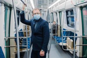 Coronavirus crisis in 2020. Man commutes to work in empty underground, uses public transport, uses protective face mask against virus, wears protective surgical mask during quarantine period photo