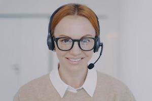 Friendly woman in headphones in call center. Face of happy employee. Customer support concept. photo