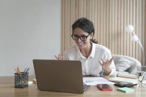 Overjoyed italian businesswoman reading great news on laptop at her workplace photo