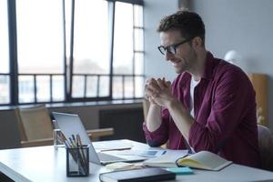 Young european man freelancer working on laptop computer, watching interesting business webinar photo