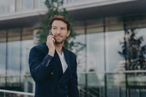empresario masculino habla por teléfono resuelve problemas urgentes plantea cerca del centro de negocios foto