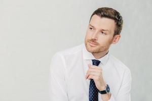 un joven pensativo mira a un lado con expresión pensativa, usa camisa blanca y corbata, aislado sobre fondo blanco con espacio en blanco para su contenido publicitario o texto promocional. jefe interior foto