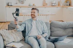 Young man in video call with friend while sitting on couch photo