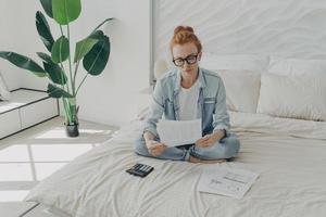 Good looking redhead European woman calculates expenses manages household budget photo