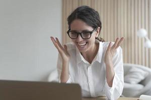 Joyful coach italian lady looks at laptop screen while communicating with students online photo