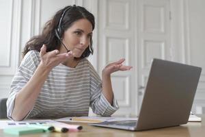 Young smiling Italian woman freelancer in headset consulting client customer via video call photo