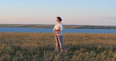 Female practicing qigong in summer fields with beautiful sunset on background photo